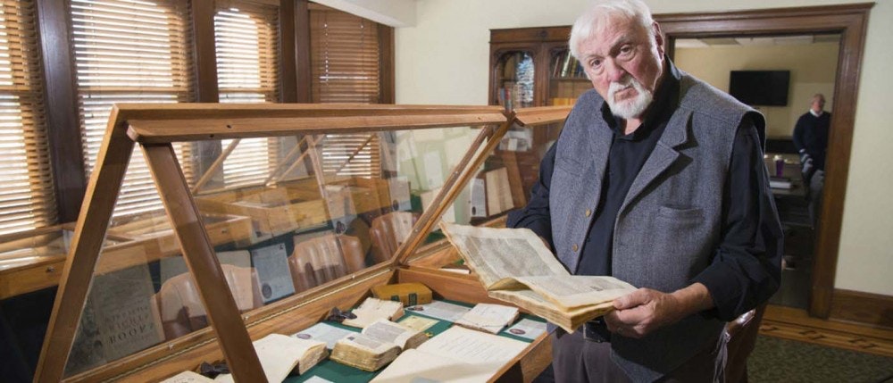 Brian Rex reading a rare book in a collection he started in 1997