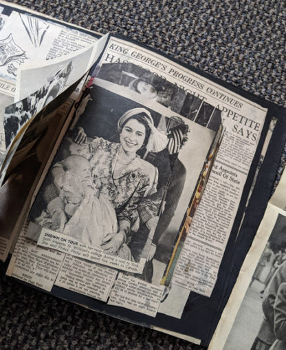 photo of Queen Elizabeth holding one of her children inside a Vintage Souvenir Book Full of early article pictures of Queen Elizabeth