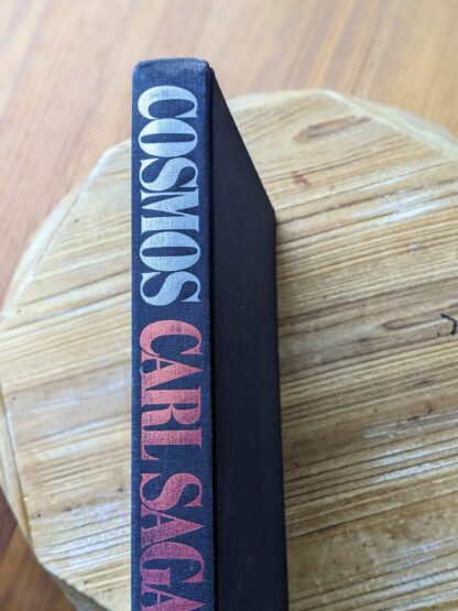 upper binding view of a 1980 copy of Cosmos by Carl Sagan without the dustjacket on