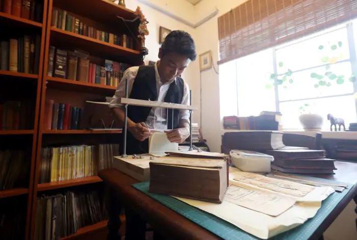 Luqman showing the process of 'threading' where pages are aligned in the sewing frame before being bound together.