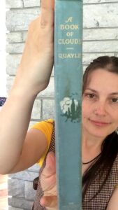 Ashley holding up a 1925 copy of A Book of Clouds by William A. Quayle