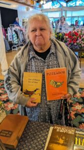 George Clutesi's niece holding up two of his books at a Craft market in Port Alberni - Ash Tree Books
